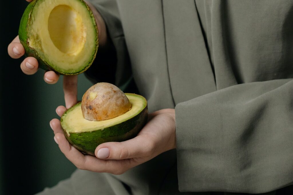 Person holding a sliced green avocado